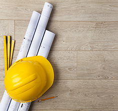 . Image - Wooden floor with rulers, rolled up whiteprints, hard hat, and pencil. Click tile image to view