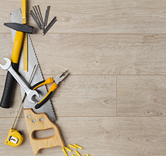 . Image - Wooden floor with nails, screws, hammer, wrench, plier, saw and measuring tapes. Click tile image to view